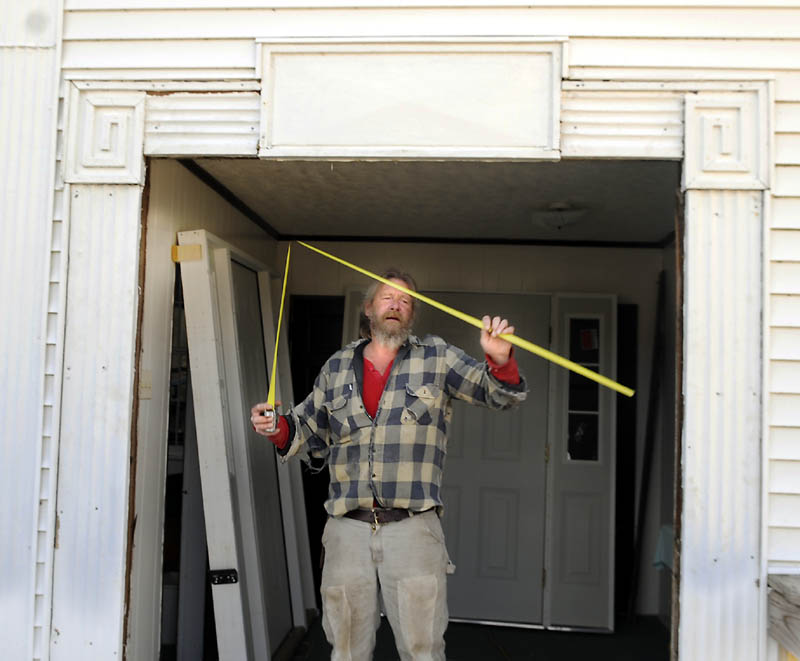 Frank Smith of New Sharon Monday measures the opening for new doors he planned to hang at the entrance of the Vienna Baptist Church. Organized in 1820 and erected in 1840, the church has served the community for over 150 years.