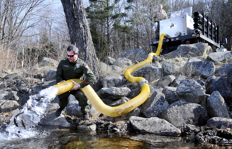 District Game Warden Steve Allarie, left, helps Department of Inland Fisheries and Wildlife hatchery manager Tom McLaughlin stock 500 brook trout into Jamie's Pond in Farmingdale on Monday. McLaughlin said hatcheries are busy putting several thousand of the 10-12 inch game fish into bodies of water across the state.
