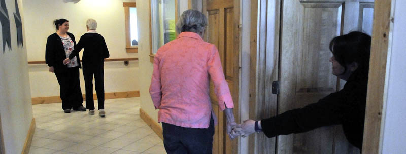 June Meres, left center, an Alzheimer's patient at Bedside Manor, tries to pull Julie Benecke, right, from her office for a walk around the facility on Belgrade Road in Oakland on Wednesday. In the background, Martha Fabian, also a resident of Bedside Manor, walks the halls with care attendant Maribeth Beland.