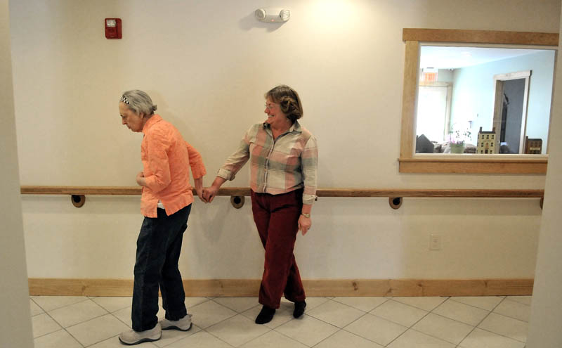 June Meres, left, grabs the hand of visitor Christine Pillsbury, as Meres roams the halls at Bedside Manor on Belgrade Road in Oakland on Wednesday.