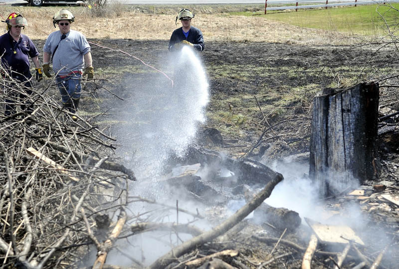 Randy Caswell, a volunteer firefighter with the Clinton Fire Department, sprays down the origin of a 5.4 acre grass fire at 434 Canaan Road in Clinton on Monday.