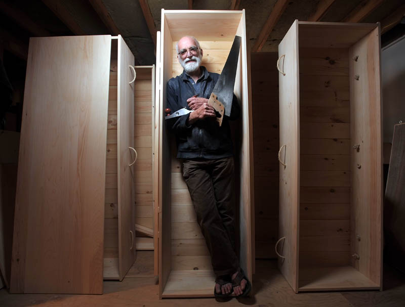 Chuck Lakin, 67, stands inside one of his handmade coffins in his workshop, in the basement of his Waterville residence, on Saturday.