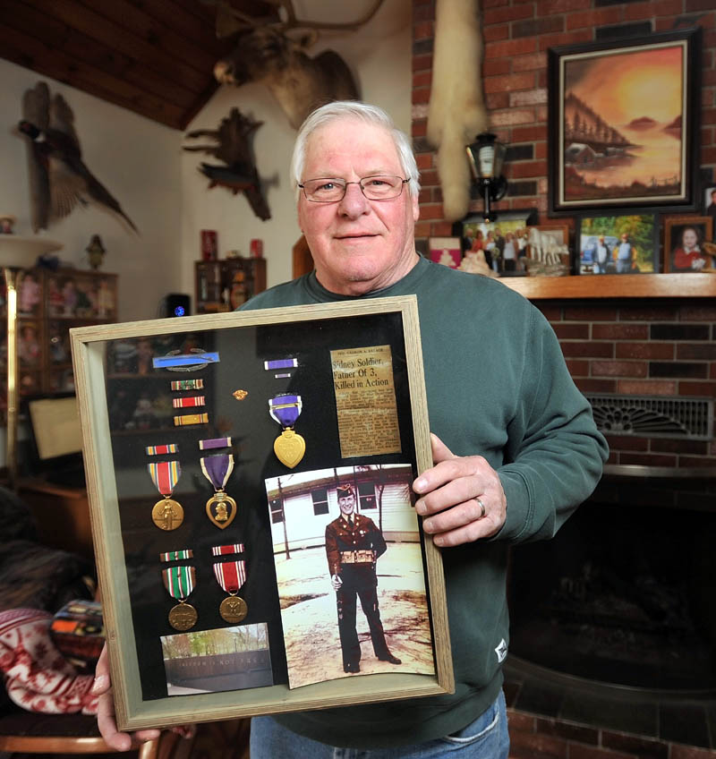 George Savage holds a picture of his father, George, at his Sidney home on Wednesday. Savage's father's remains currently reside in North Cemetery on Madison Avenue in Skowhegan and are in danger of being exposed due to erosion from Whitten Brook.
