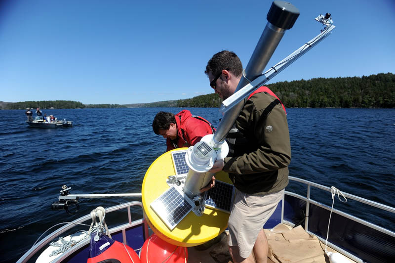 Colby College chemistry professor Whitney King, back center, and Colby College senior Matt LaPine, 22, install a research buoy named Goldie in to Great Pond in Belgrade.