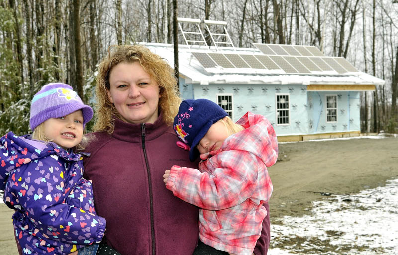 Joni Sprague and her twin, 3-year old daughters, Allie, left, and Kylie, in front of their Habitat for Humanity home,outfitted with solar panels, on Jacques Lane in Oakland on Saturday. The family will be moving in to their home in June.