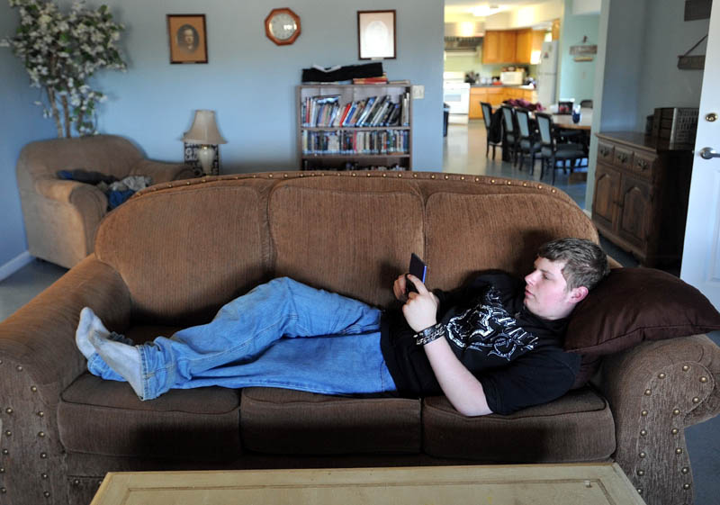Zach Brady, 17, a junior at Maine Academy of Natural Sciences, lounges on the couch in the common area at the Hall Cottage student dorm on the Goodwil-Hinckley campus in Fairfield on Thursday. The Maine School of Natural Sciences is planning to start a room and board fee for some students that live on campus.