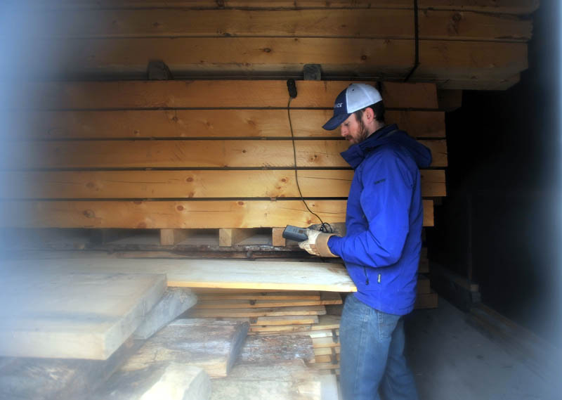Josh Saltmarsh checks the moisture content of lumber in the dehumidification kiln at The Wood Mill of Maine, on Mercer Road in Mercer, on Friday.