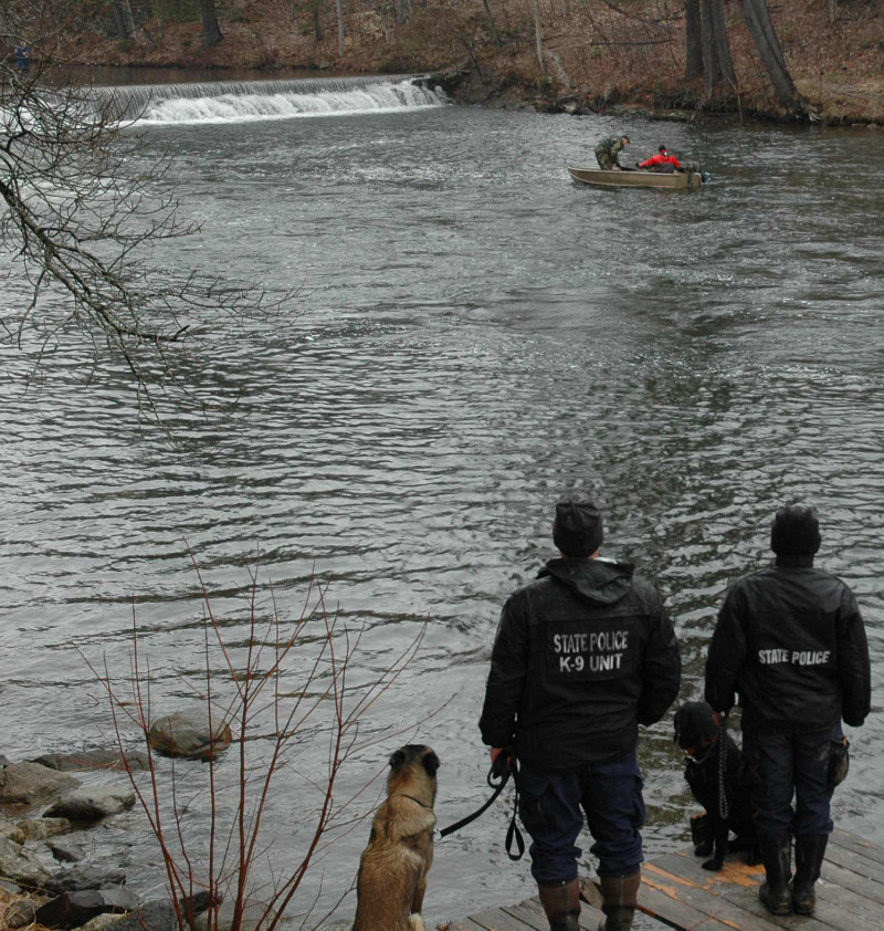 A recovery team uses a boat to retrieve the body of Romeo Parent, 20, from Jug Stream in East Monmouth on Friday. In the foreground are canine units which discovered the body.