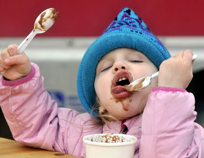 Adrianna Lombardi, 2, digs in to some fresh ice cream from Stone Fox Farm Creamery, in spite of the cool temperatures and rain, at the opening day of of the Waterville Farmer's Market at The Concourse on Thursday.