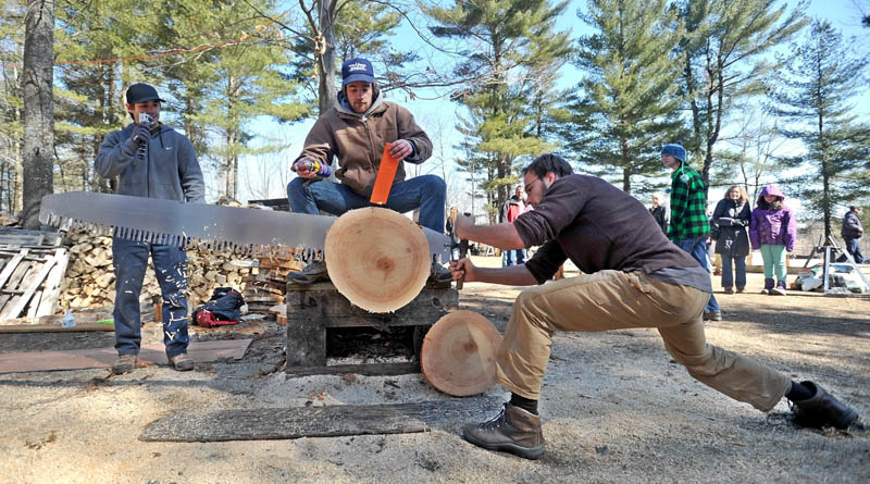 Teague Henkle, 21, from the University of Vermont, greases a saw as teammate Eric Donnelly competes in the single-buck comepition at Colby College's annual Muddy Jack & Jill Meet in Waterville on Saturday.