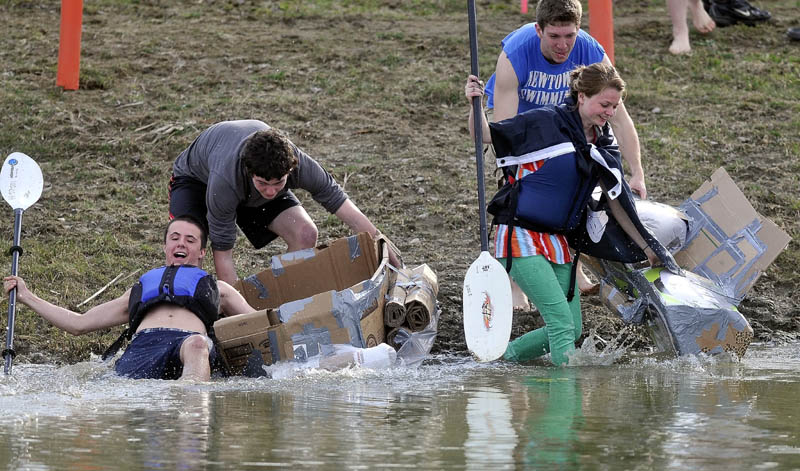 Chris Iacozzi, 18, left, slips as he races into the water as Summer Nay, 20, drags her cardboard kayak in to the water during the first cardboard kayak race at Unity College on Friday.