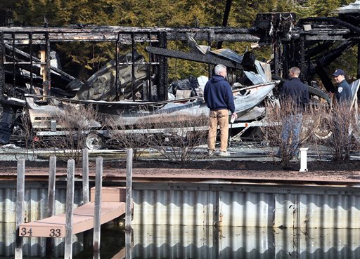 Investigators inspect what's left of boats on Monday after a fire damaged about 30 boats at the Riveredge Marina in Ashland, N.H.