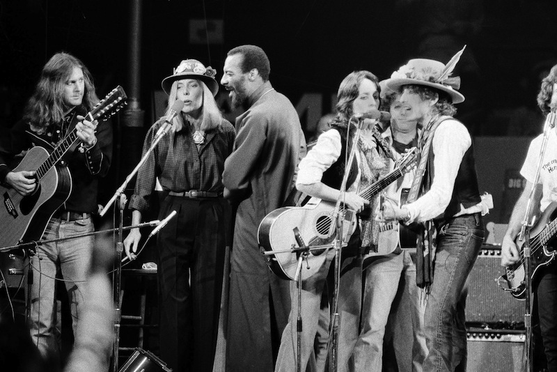 In this Dec. 1975 file photo, musicians Roger McGuinn, Joni Mitchell, Richie Havens, Joan Baez and Bob Dylan perform the finale of the The Rolling Thunder Revue, a tour headed by Dylan.  (AP Photo, File)