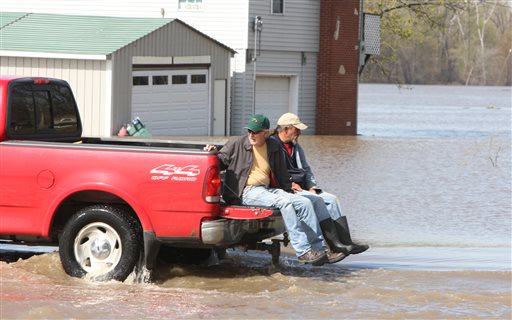 A pickup truck from the Grafton Marina takes two men across a flooded section of marina entrance road on Monday in Grafton, Ill. Floodwaters from the Mississippi River have closed the main entrance forcing residents to use a back road away from the river.