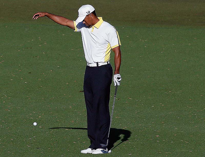 Tiger Woods takes a drop on the 15th hole after his ball went into the water during the second round of the Masters golf tournament Friday. On Saturday, Woods was slapped with a two-stroke penalty.