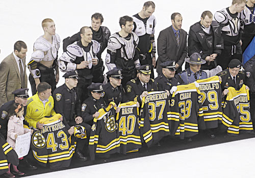 THANK YOU: First responders, members of law enforcement and Boston Marathon officials hold Boston Bruins jerseys as they gather with members of the team, back, on the ice following the Bruins game against the Florida Panthers on Sunday at the TD Garden in Boston. In a change requested by fans, Bruins players presented their jerseys to some of those who offered help in the minutes and days following the marathon bombings on Monday.