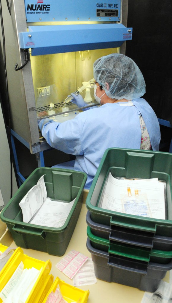 Pharmacy technician Suzanne Goddard works under a hood, preparing intravenous bags of medicines, in the sterile room on April 12, at Kennebec Pharmacy & Home Care in Augusta.