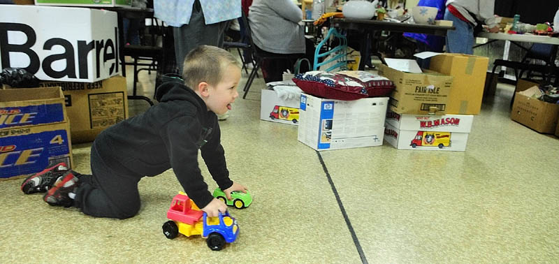 Riley Lenhart, 3 of Gardiner, takes a test drive with some toy trucks that his mother, Tona Libby, bought for him on Saturday at an charity indoor yard sale in the Knights of Columbus Council 1299 Hall in Gardiner. It was a fundraiser for Jacob Lamoreau to get hearing aids, and the Knights group was donating funds from concession and table rentals.