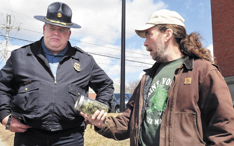 Marijuana advocate Donald Christen shows a jar of marijuana to Skowhegan Deputy Police Chief Dan Summers during the Patriots Day "smoke-in" on the steps of the Somerset County courthouse on Monday. The protest was part of Christen's continued efforts to draw attention to legalizing marijuana. Christen is a medicinal marijuana patient and can legally possess the drug.