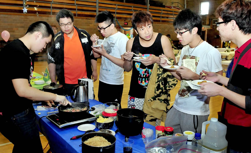 Maine Central Institute students line up to try the Thai fish plate being prepared by Joseph Yeh during International Food Festival in Pittsfield on Saturday.