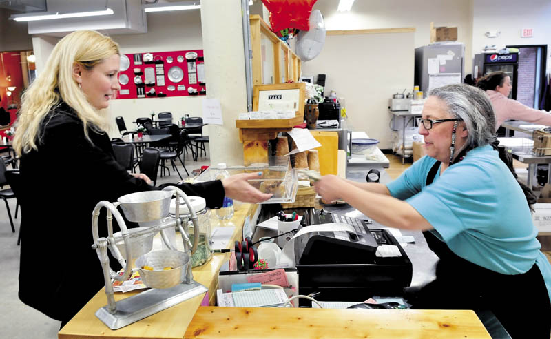 The Button-Down Cafe owner Maureen Kibler, right, gives change to customer Sarah Brown at the new restaurant in the Hathaway Creative Center in Waterville. In back, assistant manager Samantha Gagne prepares an order.