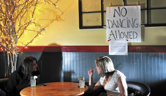 Ashley Gosline, right, chats with Hiedi LaLiberte while listening to the The Scolded Dogs band at Higher Grounds in Hallowell Friday. The Office of the State Fire Marshal recently cracked down on establishments that permit dancing that don't meet code. The Scolded Dogs normally play to a packed house with several people dancing.