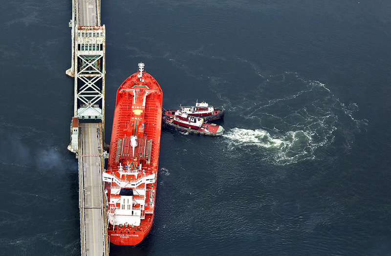 Tugboats seen in this aerial photograph hold the Harbour Feature in place against the Sarah Mildred Long Bridge in Kittery on Monday, after the tanker snapped its mooring lines at the New Hampshire State Pier in Portsmouth, N.H.