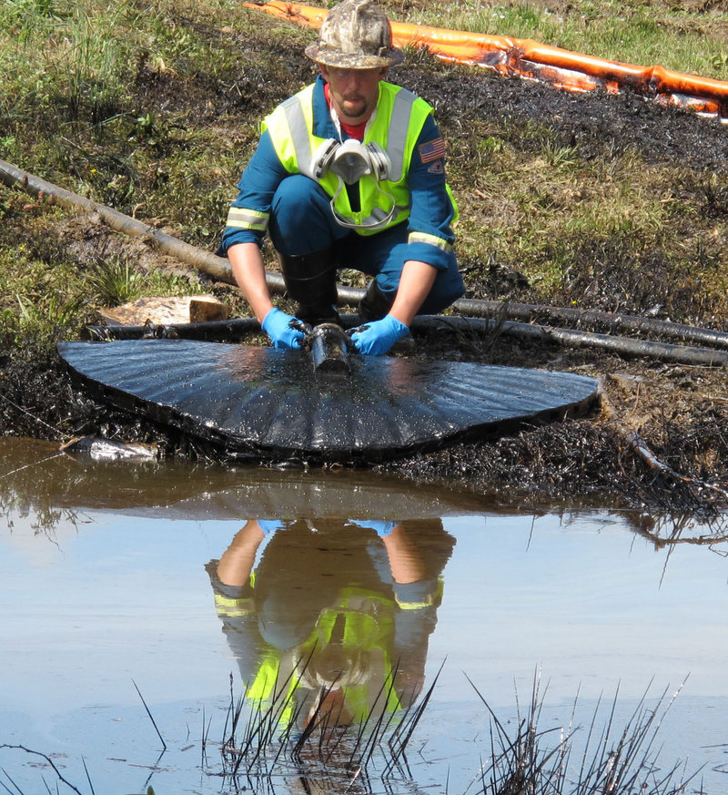 A worker from an oil cleanup crew siphons oil from a drainage channel for Lake Conway in Conway, Ark., on Sunday. There were 364 pipeline spills last year.