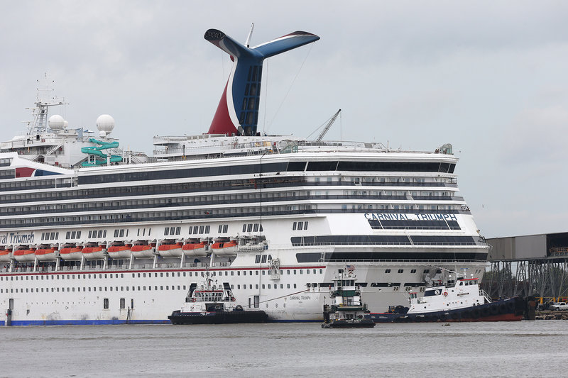 Tug boats maneuver around the Carnival Triumph as it rests against a dock on the Mobile River after becoming dislodged from its mooring during high winds Wednesday.