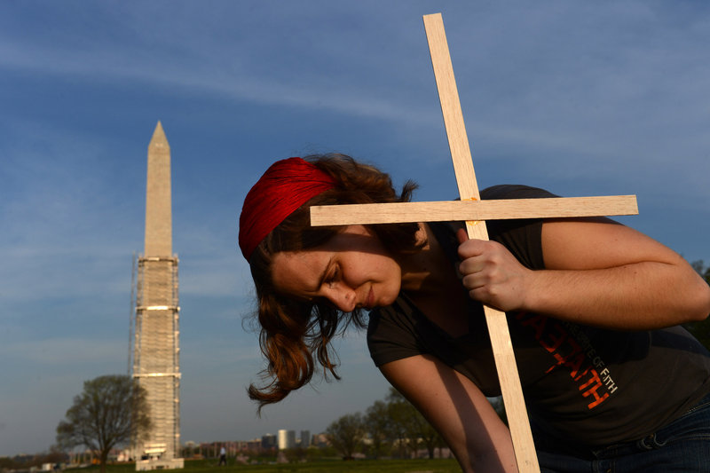 Janelle Tupper places a cross, one of about 3,300 symbolic markers assembled Thursday on the National Mall in Washington to represent victims of gun violence that occurred after the December 2012 shootings in Newtown, Conn.