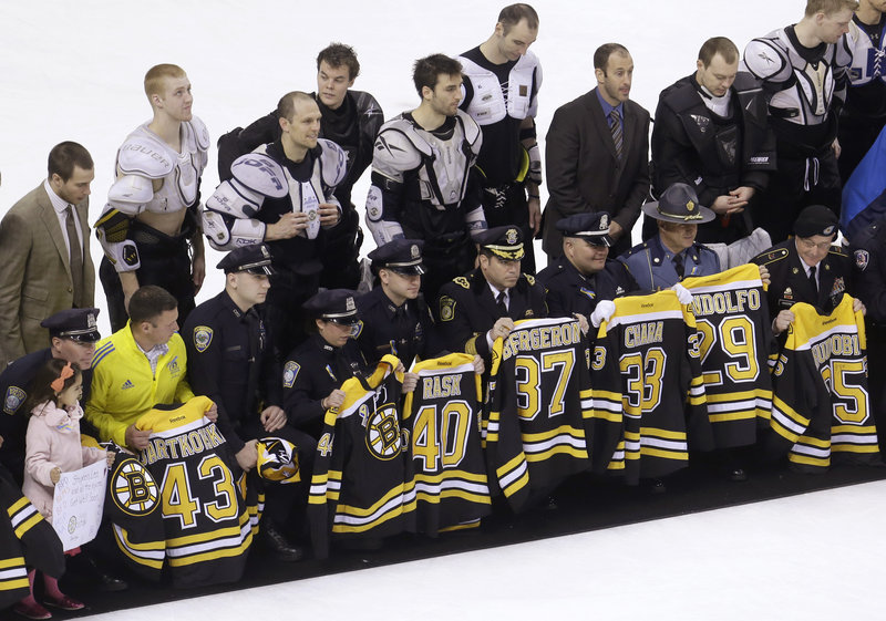 First responders, members of law enforcement and Boston Marathon officials hold Boston Bruins jerseys they received in the Bruins’ “Shirt Off Our Backs” ceremony.