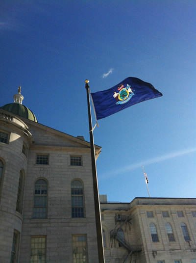 The Maine flag flies outside the State House in Augusta.
