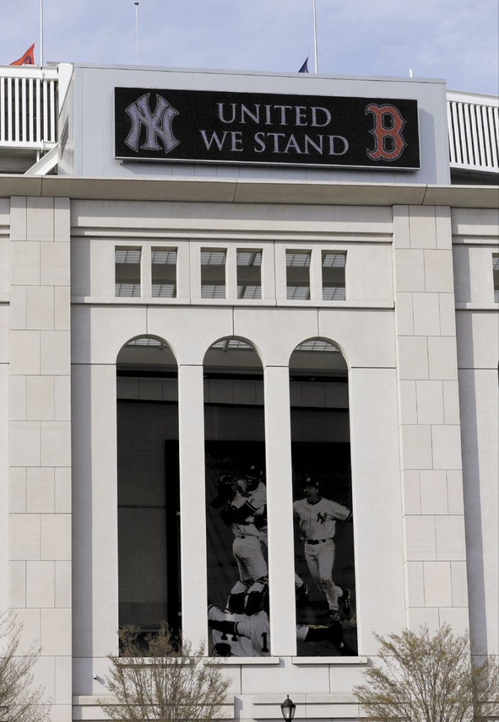 A sign that reads "United We Stand" between logos for the New York Yankees and the Boston Red Sox appears at the top of Yankee Stadium before a baseball game in New York, Tuesday, April 16, 2013. The message was displayed in the wake of the Boston Marathon explosions. (AP Photo/Kathy Willens)