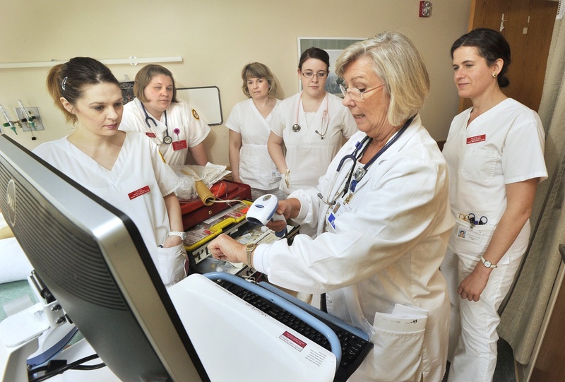 Betsy Moorhouse, a Central Maine Community College instructor, demonstrates log-on procedures for students using a mobile bedside medication verification computer in April.