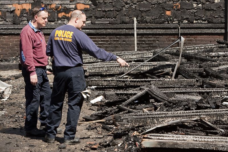 Fire investigators on Saturday morning inspect the rubble at what is believed to be the fire’s origin – the garage of a condemned building – for clues about its origin.