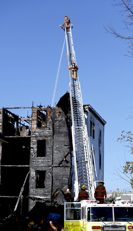 Firefighters spray water on the roof of a vacant apartment building on Bartlett Street in Lewiston on May 6, 2013 following a third major fire in eight days in the downtown area.