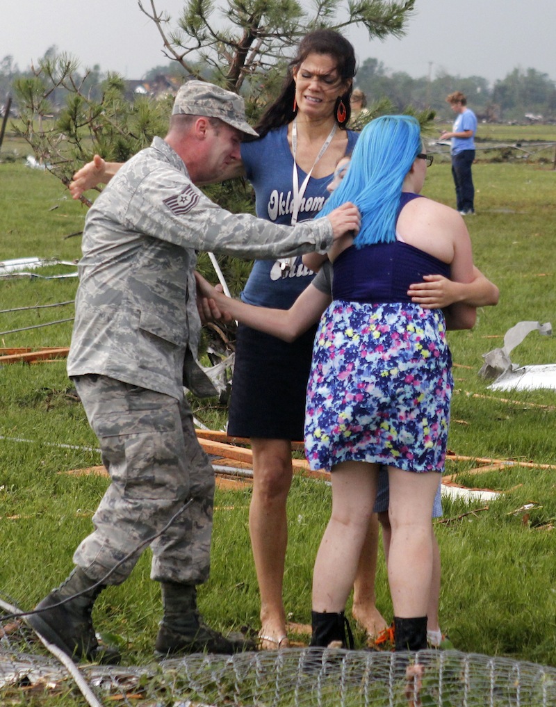 T. Sgt. Robert Raymond, left, runs to embrace his son Ethan, 11, center partially obscured, with his daughter Lily, 17, right, at Briarwood Elementary school after a tornado destroyed the school in south Oklahoma City on Monday, May 20, 2013. (AP Photo/The Oklahoman, Paul Hellstern)