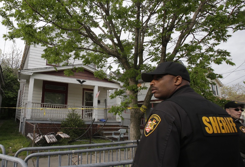 A sheriff's deputy stands outside a house from which three women escaped Tuesday in Cleveland.