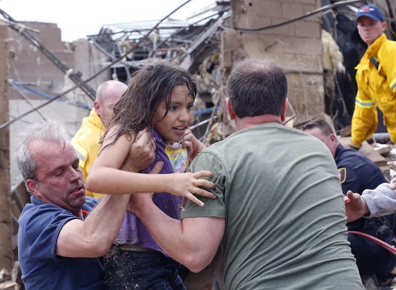 A child is pulled from the rubble of the Plaza Towers Elementary School in Moore, Okla., and passed along to rescuers Monday, May 20, 2013. A tornado as much as a mile (1.6 kilometers) wide with winds up to 200 mph (320 kph) roared through the Oklahoma City suburbs Monday, flattening entire neighborhoods, setting buildings on fire and landing a direct blow on an elementary school.(AP Photo Sue Ogrocki)