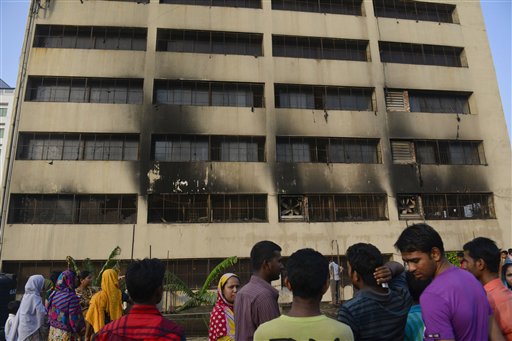 Workers stand outside an 11-story building that houses the Tung Hai Sweater Ltd. factory and apartments after a fire in Dhaka, Bangladesh on Thursday.