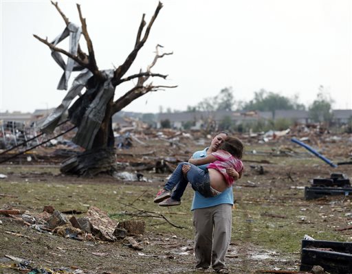A woman carries a child through a field near the collapsed Plaza Towers Elementary School in Moore, Okla., on Monday after a tornado as much as a half-mile wide with winds up to 200 mph roared through the Oklahoma City suburbs.