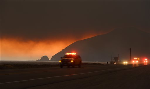 Fire department personnel drive along Pacific Coast Highway near Point Mugu as a thick layer of smoke sits overhead during a wildfire that burned several thousand acres on Thursday in Ventura County, Calif.