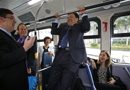 Wang Chuanfu, founder and chairman of Chinese automaker BYD Co., center, does a chin-up in an electric bus during a visit by California Gov. Jerry Brown at the headquarters in Shenzhen, China, on April 16, 2013.