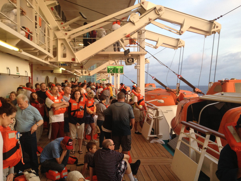 In this photo provided by passenger Marc Bell, passengers aboard the Royal Caribbean's Grandeur of the Seas cruise ship muster at sunrise Monday after a fire broke out during the ship's voyage from Baltimore to the Bahamas.