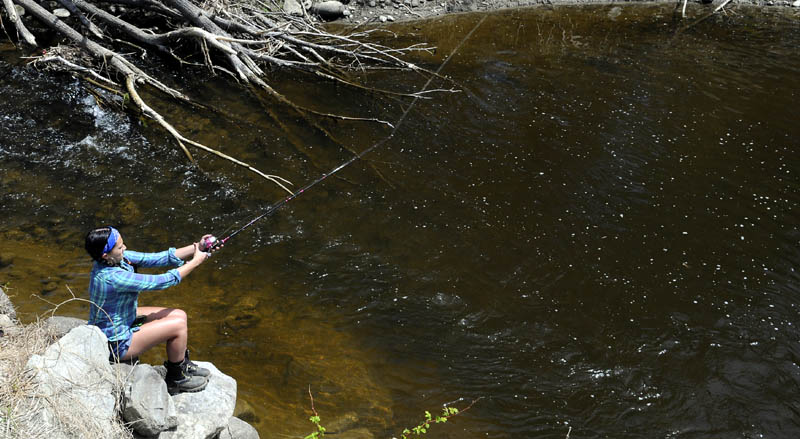 Kaysie Dostie casts into Bond Brook on Monday while fishing on her grandfather's land in Augusta. Dostie said she lost a fish but expected a few more to strike her worm.