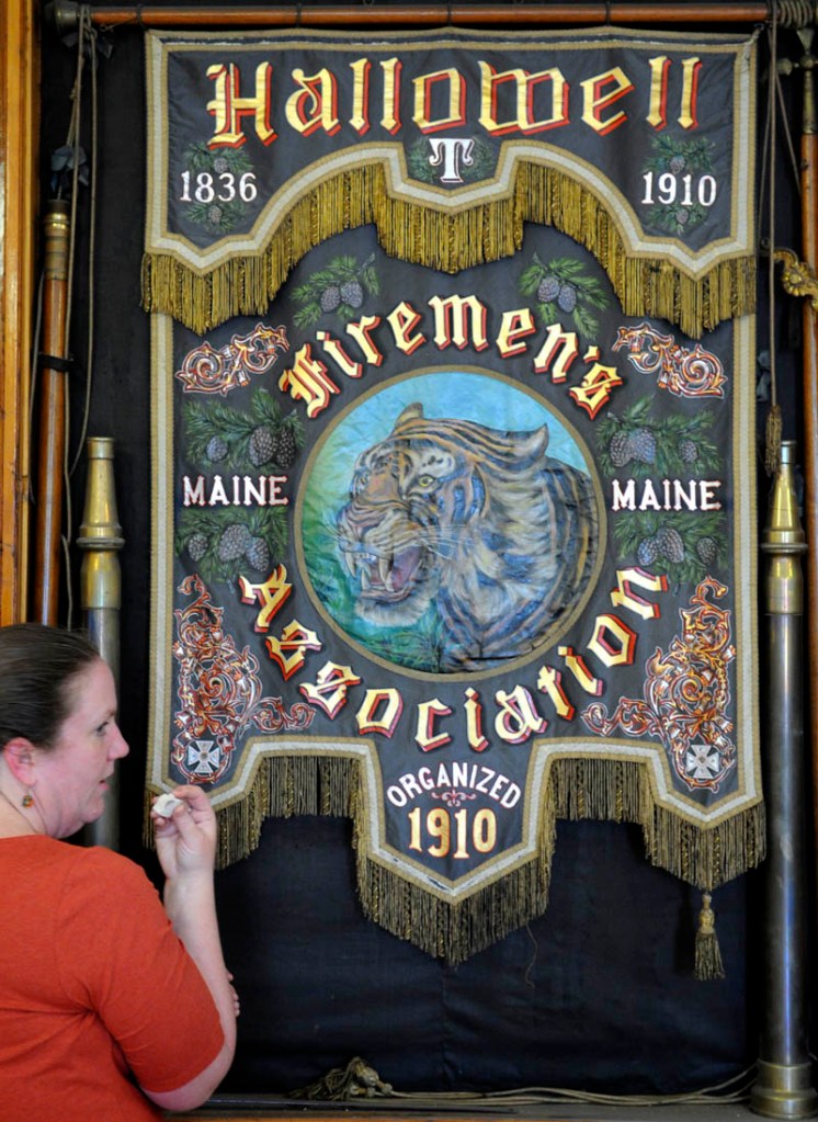 Camille Myers Breeze inspects a smudge sample from the painted silk banner hanging at the Hallowell Fire Department on Wednesday. Breeze, of Museum Textile Services of Andover, MA, assessed the condition of the banner that is believed to date from 1910 to determine its condition and work warranted to restore it. The banner was carried during processions at musters by the Hallowell Firemen's Association "It's one of the nicest painted silk banners I've ever seen," Myers Breeze said. The tiger depicted in the banner was the name of the department's engine at the turn of the 20th century.