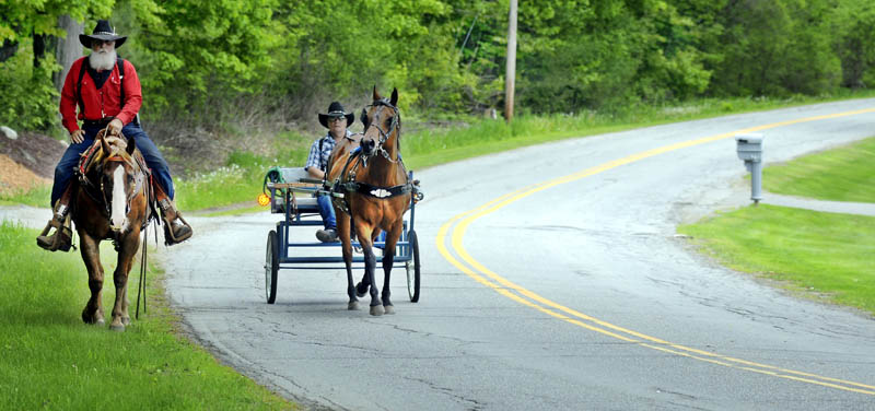 Dan Boyd, left, and his son, Gary, ride through Vassalboro Thursday with a pair of steeds during their nationwide tour of the United States on horseback. The riders have crossed several southern states since their journey commenced in September of 2012 and hope to cover the eastern seaboard this year. "The Lord put it in my heart," Dan Boyd, a pastor from Kansas, said. "We plan to preach on the way."