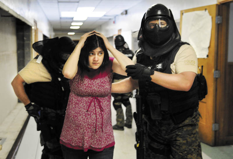 Kaitlynn Littlefield is escorted Wednesday from the former Hodgkins Middle School in Augusta by a member of Augusta Police Department's special response team during hostage negotiation training in Augusta. Littefield and four colleagues from Crisis in Counseling portrayed hostages while law enforcement students from Thomas College and the University of Maine at Augusta depicted armed gunmen barricaded in a classroom, according to Augusta Police Lt. Kevin Lully. Negotiators from the Lewiston and Augusta Police Departments practiced persuading the hostage takers to surrender during the day-long training.
