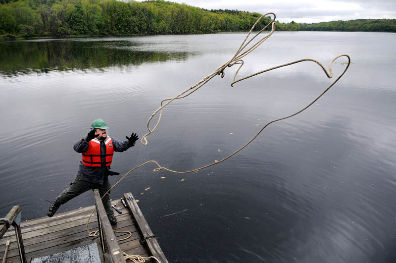 Maine Bureau of Parks and Lands employee Matt Myshrall tosses a line to shore from a dock he helped install Monday on the Kennebec River in Hallowell. The state is laying out the docks along the river for summer.