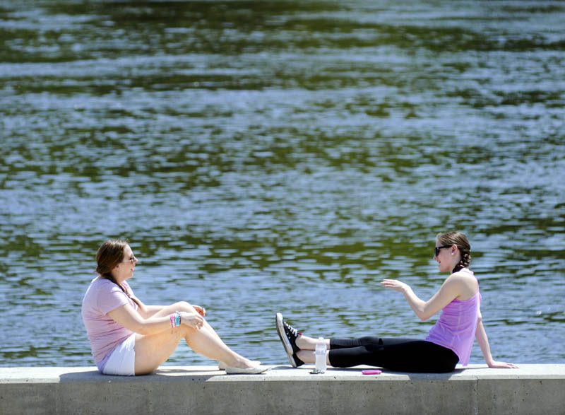 Simera LeBlanc, left, and Katie Formanski, of Litchfield, share some sun Thursday on the bulkhead along the Kennebec River near LeBlanc's home in Hallowell. The temperature reached into the mid 80s.